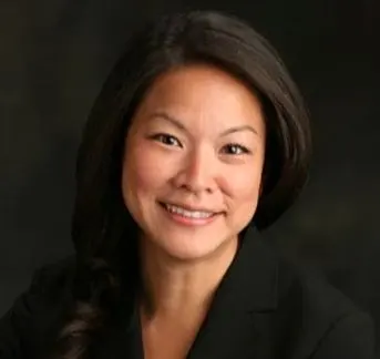 An asian woman with long dark hair in a black blazer.