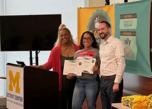 3 people standing behind a podium with certificates.