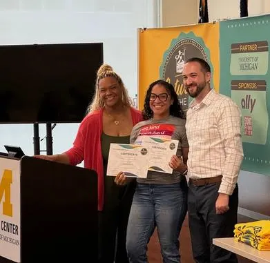 3 people standing behind a podium with certificates.