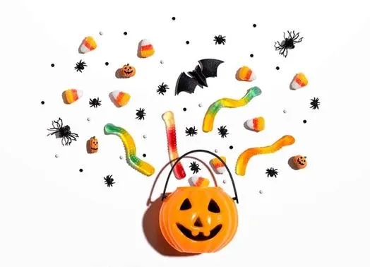 a plastic jack-o-lantern bucket with candy, bats and spiders coming out of it