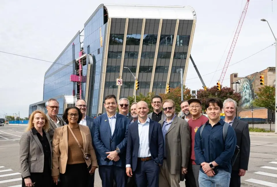 A group of people dressed in business casual wear standing in front of a glass building under construction.